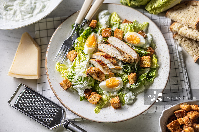 健康的凯撒沙拉，配有罗马生菜、烤鸡胸肉、鸡蛋、面包丁、酸奶酱和帕尔马干酪。图片素材