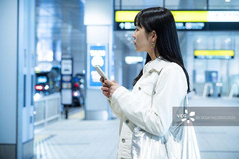 年轻女性在现代公交/火车站使用智能手机图片素材