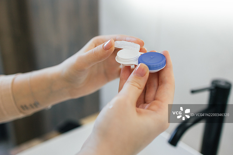 手握隐形眼镜盒的双手在浴室里图片素材