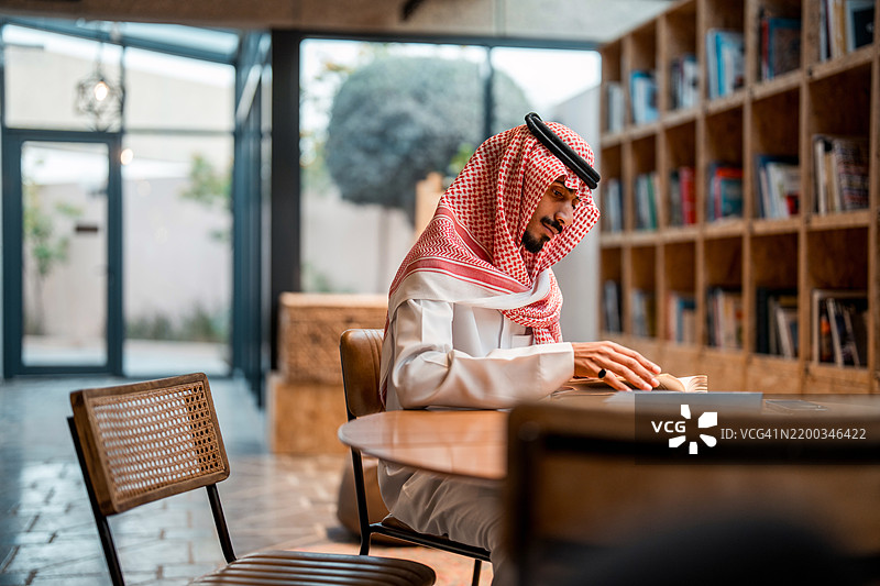 年轻的阿拉伯商人在现代办公室阅读图片素材