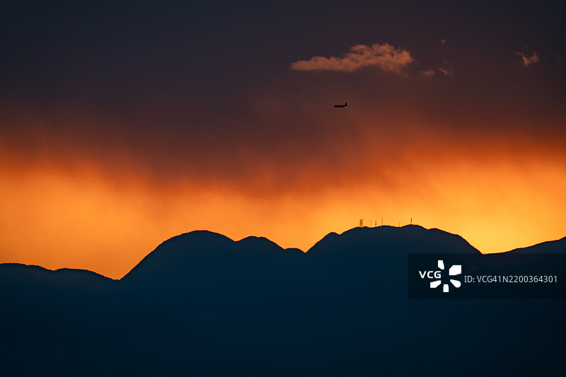 在日本神奈川的日落山脉上空飞行的飞机图片素材