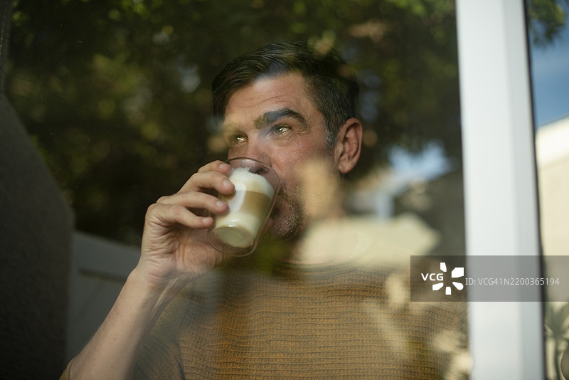 思考、饮品和窗边的男人，享受咖啡带来的宁静、平和与放松，手中拿着拿铁进行反思。早晨的日常、饮料和成熟的人士，手握杯子，寻找灵感、规划和美景。图片素材