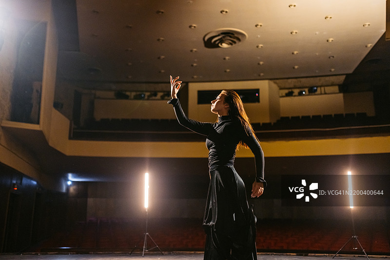 年轻女性在空旷的剧院中表演即兴舞蹈图片素材