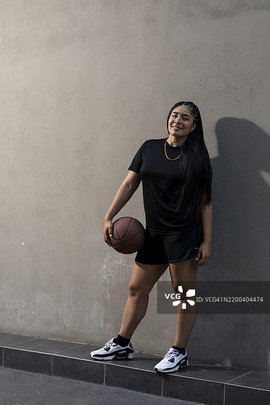 年轻女性靠在墙上手持篮球图片素材
