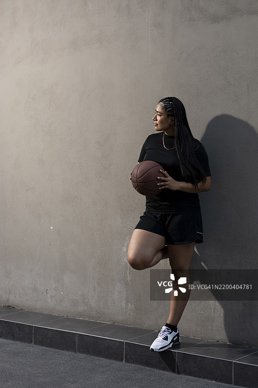 年轻女性靠在墙上手持篮球图片素材