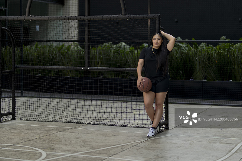 年轻女性在球场上摆姿势拿着篮球图片素材