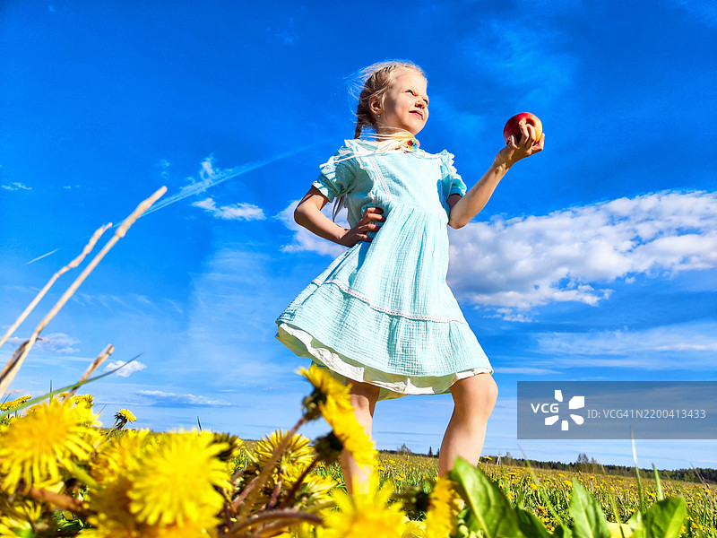 穿着蓝色裙子的年轻女孩自信地站在苹果中间图片素材