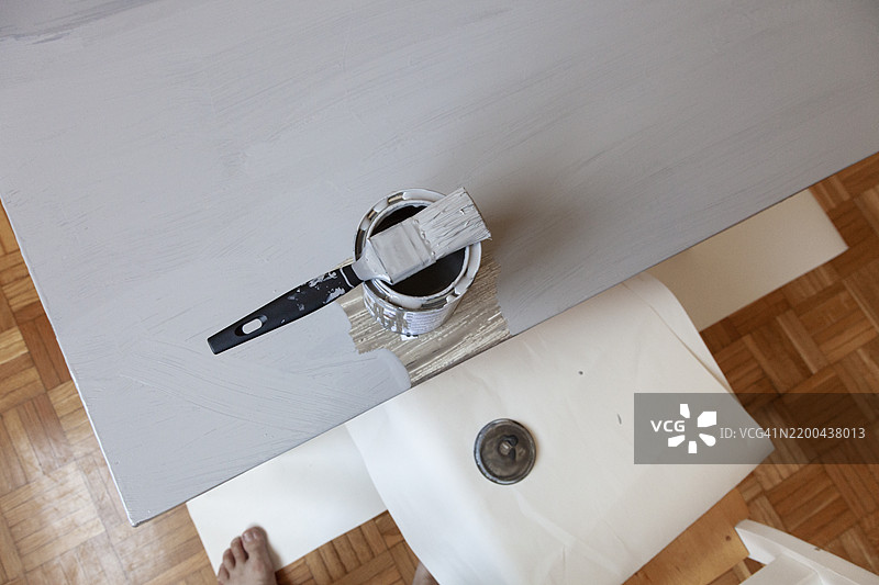 几乎完全涂成浅灰色的旧桌子，上面有一个罐子和一把刷子图片素材