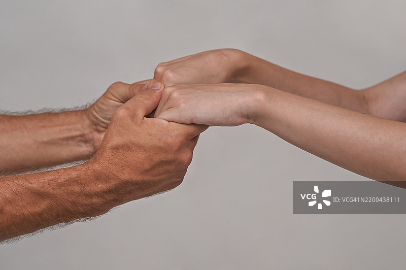 白色背景下男性手中握着女性手的特写图片素材