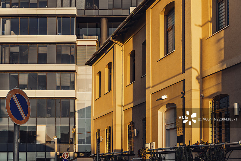 翻新后的老住宅楼与现代办公大楼在日落时分的对比图片素材