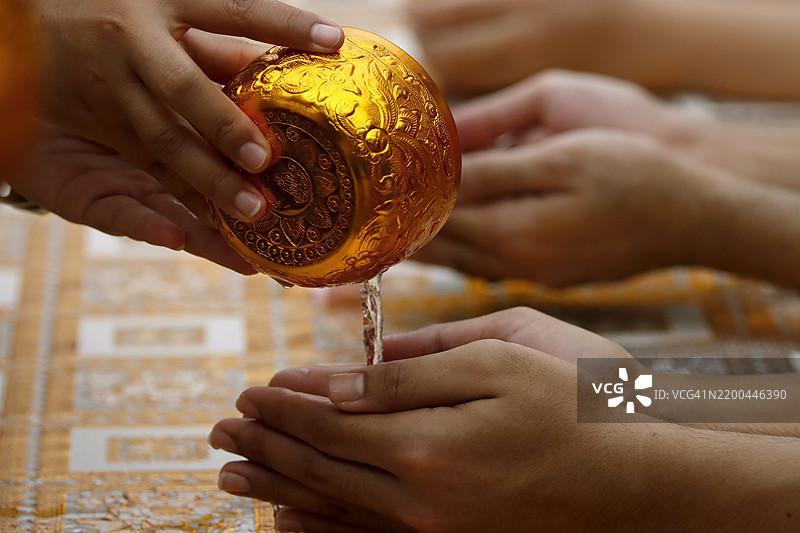 泰国人用手将水倒在僧侣的手上（沐浴），倒水是宋干节的主要仪式之一。宋干节是泰国的新年。图片素材