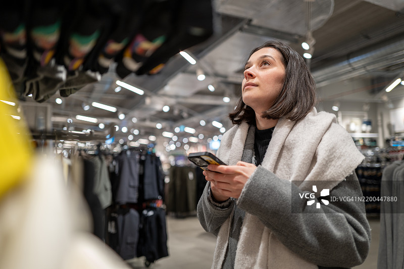 顾客在零售店购物时使用智能手机图片素材