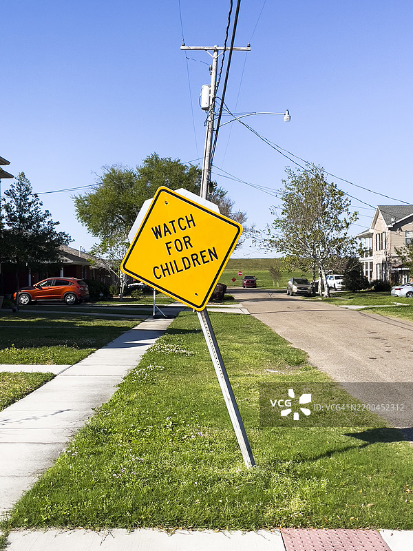 倾斜的儿童注意标志，背景是郊区街道和堤坝图片素材