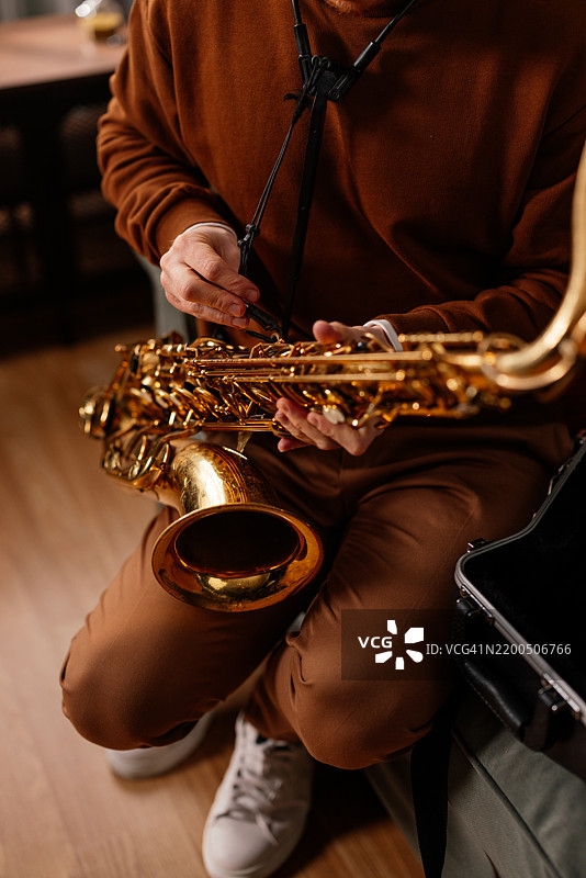 音乐家在演奏前调整萨克斯风的颈带图片素材