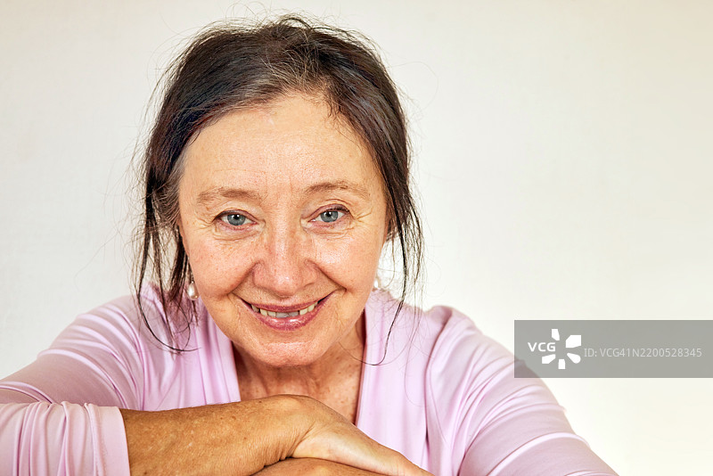 微笑的老年女性肖像，双手交叠在一起图片素材
