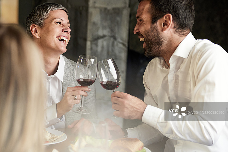 快乐的商务情侣在餐厅享用午餐时举杯庆祝。图片素材