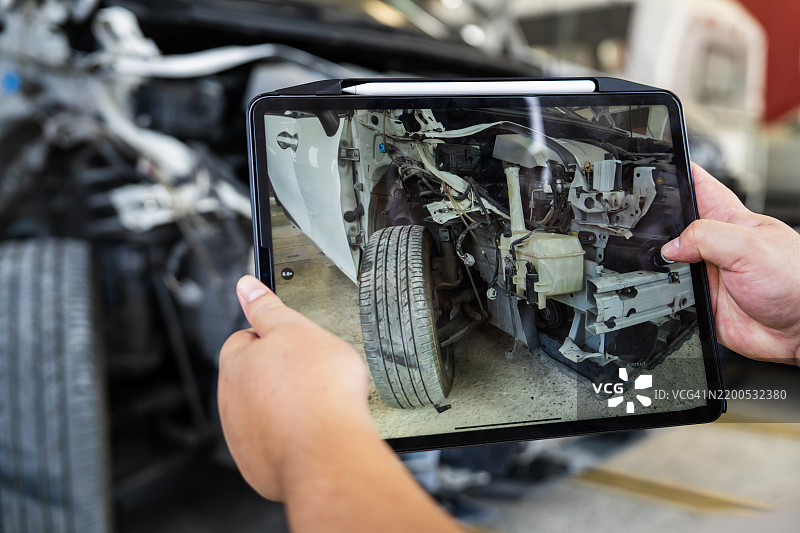 平板电脑显示汽车维修车间的车辆损伤评估图片素材