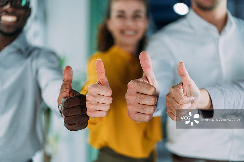 快乐的商务人士在办公室里竖起大拇指。图片素材