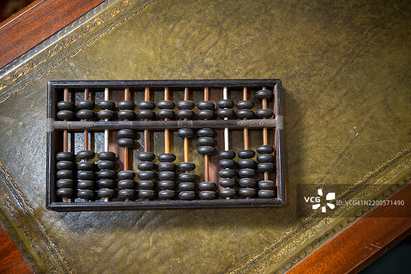 古董算盘放在复古书桌上，象征着传统计算方法。通过这个经典的数学工具探索数字历史。图片素材