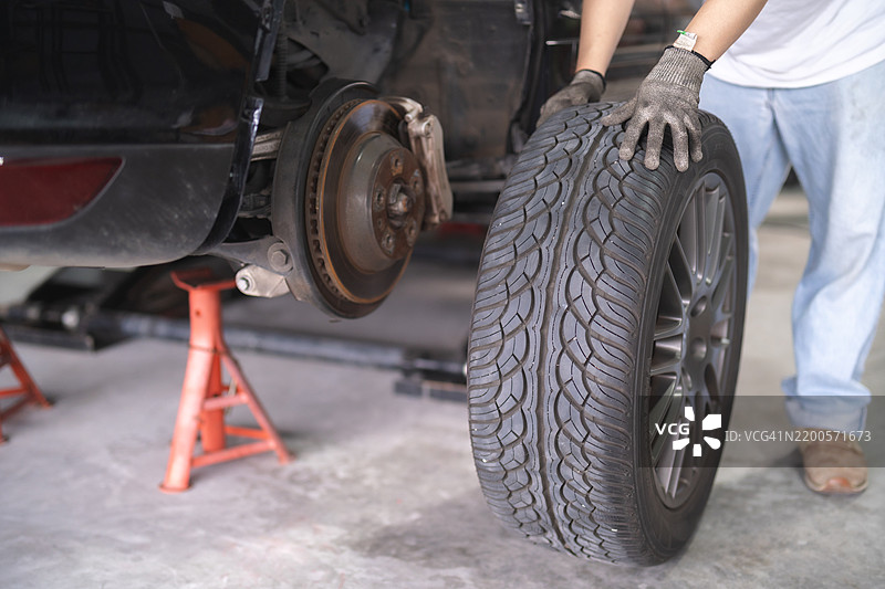 汽车维护：技师熟练地更换汽车上的磨损轮胎。今天就通过专业的轮胎服务提升安全性和性能。图片素材