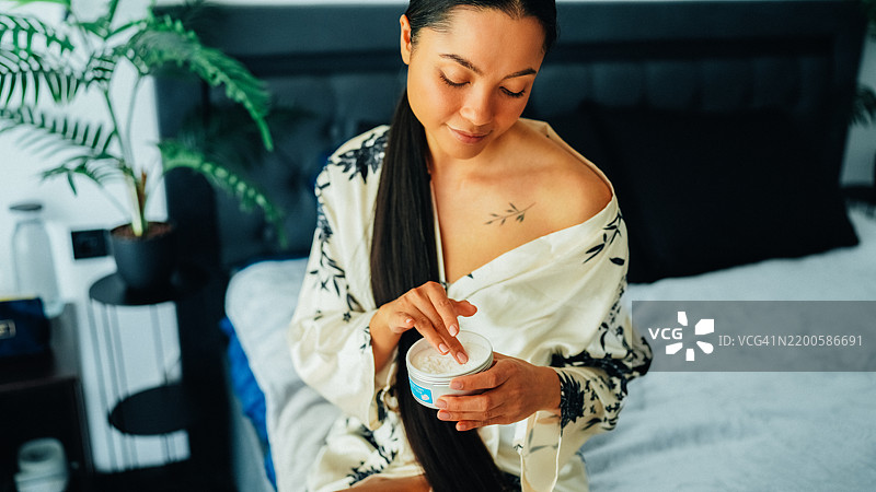 在家中使用乳木果身体乳的女性图片素材