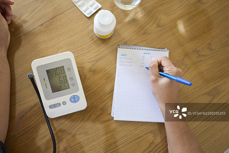 男子在健康日记中记录血压结果图片素材