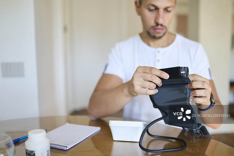 男子准备血压监测仪进行日常测量图片素材