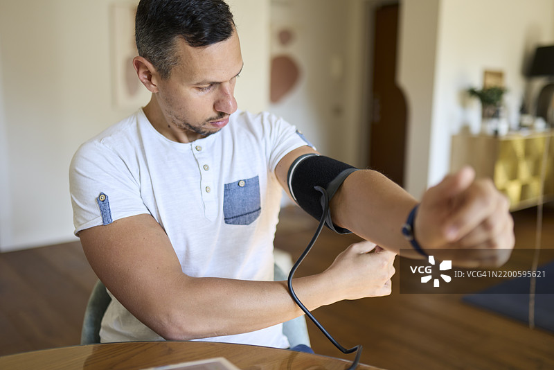 男子准备血压监测仪进行日常测量图片素材