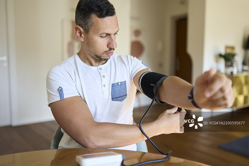 男子准备血压监测仪进行日常测量图片素材