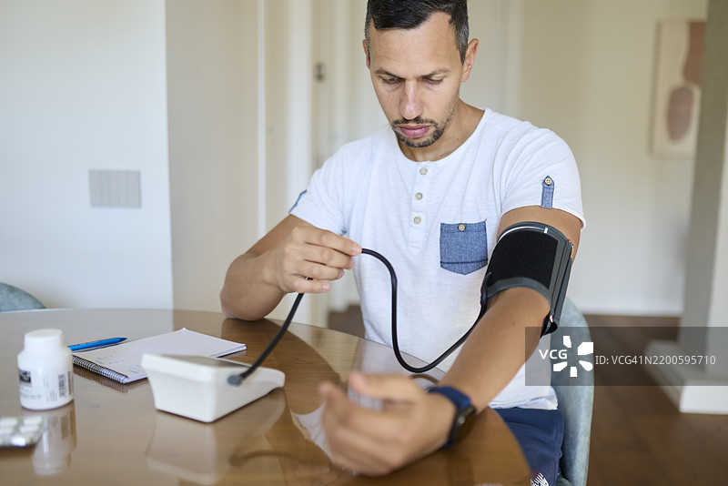 男子准备血压监测仪进行日常测量图片素材