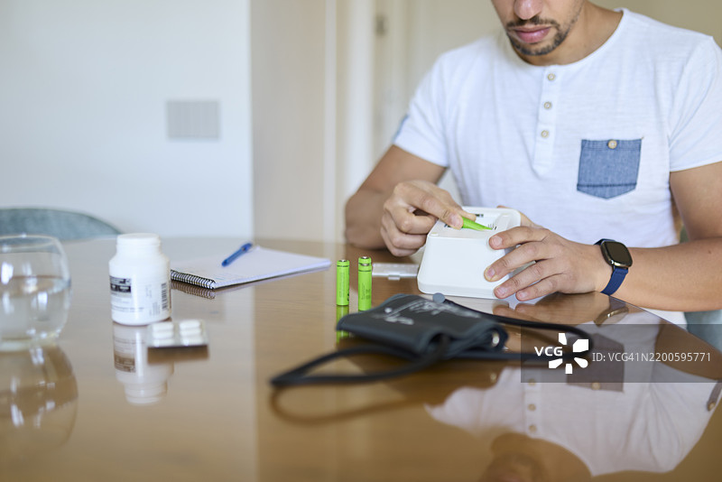 男子在更换血压监测仪的电池图片素材