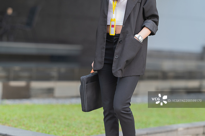 亚洲年轻女性商务人士在户外走向办公室，手提包图片素材