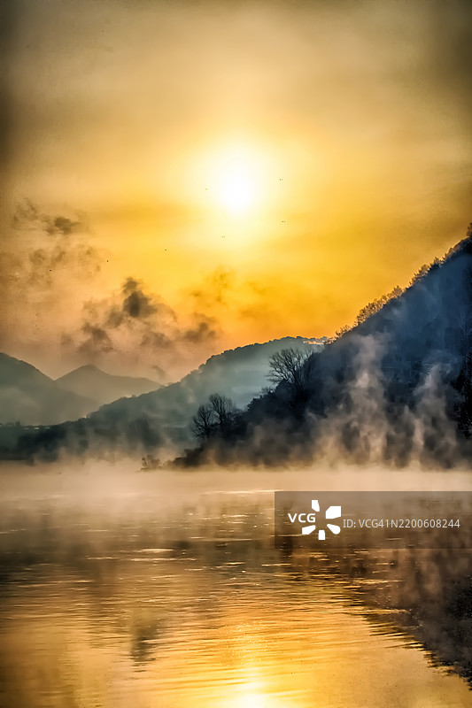 金色日出映照在雾气弥漫的湖泊和山脉上图片素材