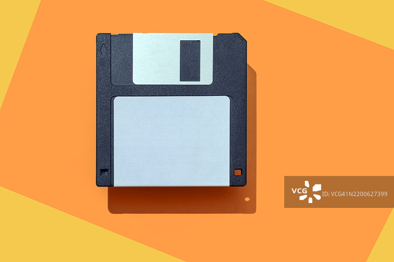 黑色复古3.5英寸软盘置于橙色和黄色背景上图片素材