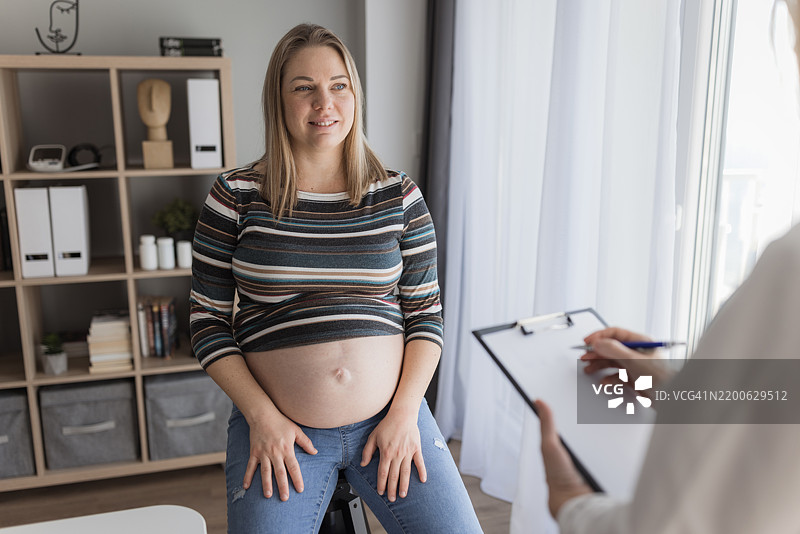 快乐的孕妇在医生办公室里图片素材