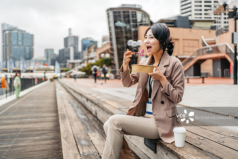 年轻的亚洲女商人在澳大利亚悉尼达令港的码头上吃沙拉图片素材