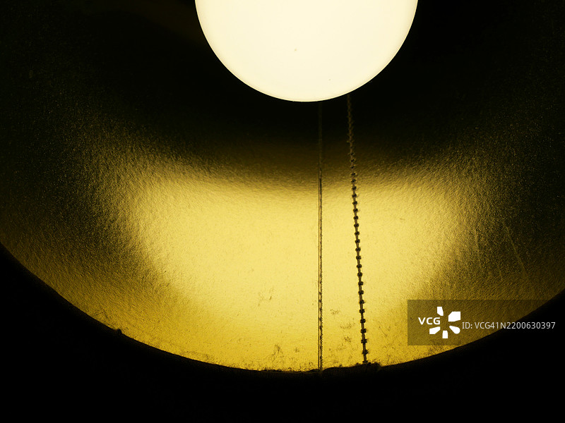 灯罩内点亮的灯泡特写（低角度视图）。自然色彩。英国伦敦。图片素材