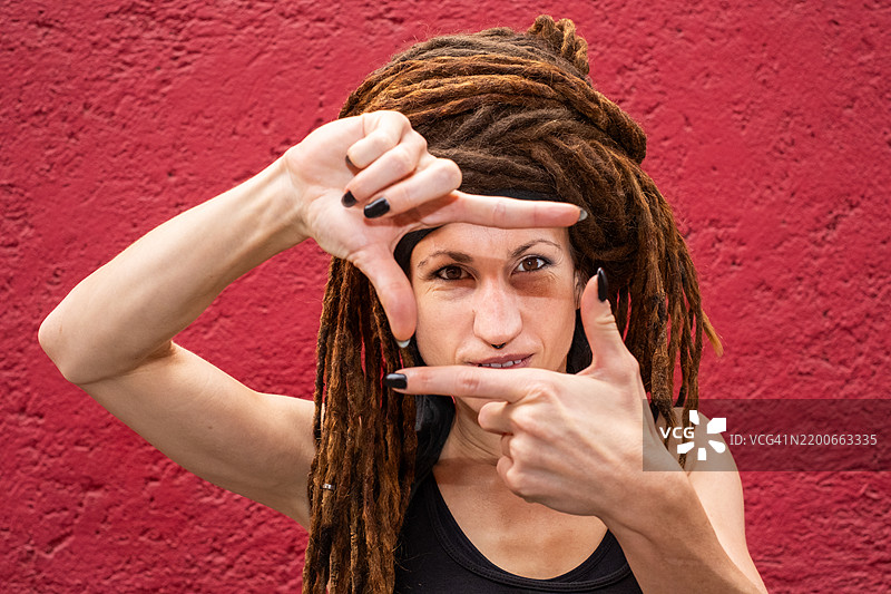 戴着头巾的白人女性，扎着脏辫，正看着镜头，用手和手指做出框架，摄影，定格瞬间图片素材