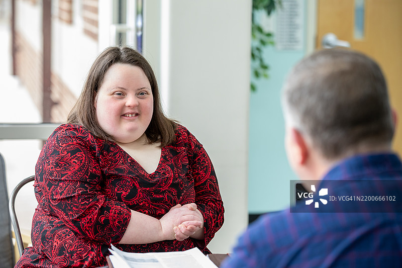 一位年轻的唐氏综合症女性正在与潜在雇主进行面试。图片素材