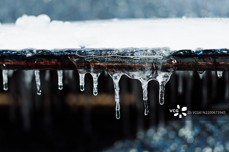 冰冷金属表面上悬挂的冰柱特写图片素材