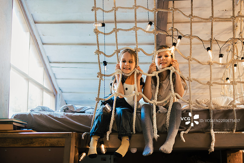 两个快乐的姐妹在阁楼卧室的绳网中玩耍图片素材