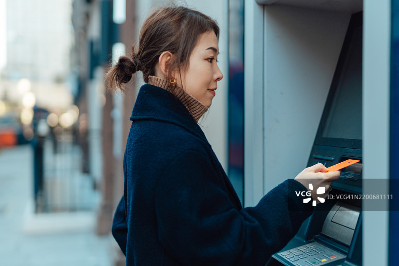 年轻的亚洲女性将银行卡插入自动取款机以查询账户余额并提取现金图片素材