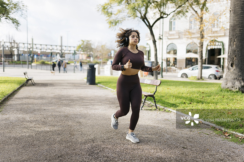 年轻的运动女性在城市公园跑步图片素材