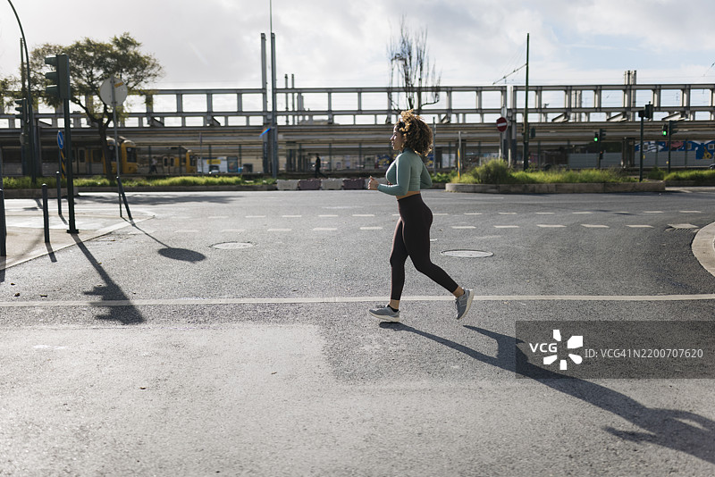 年轻的运动女性在白天的城市中跑步图片素材