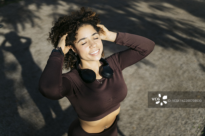 年轻的运动女性在户外训练后放松，抓着头发。图片素材