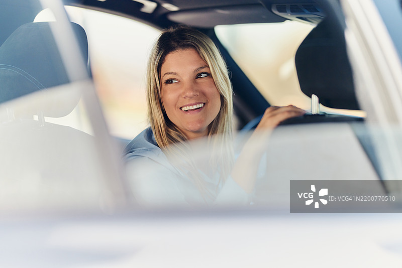 快乐的女商人在倒车停车。图片素材