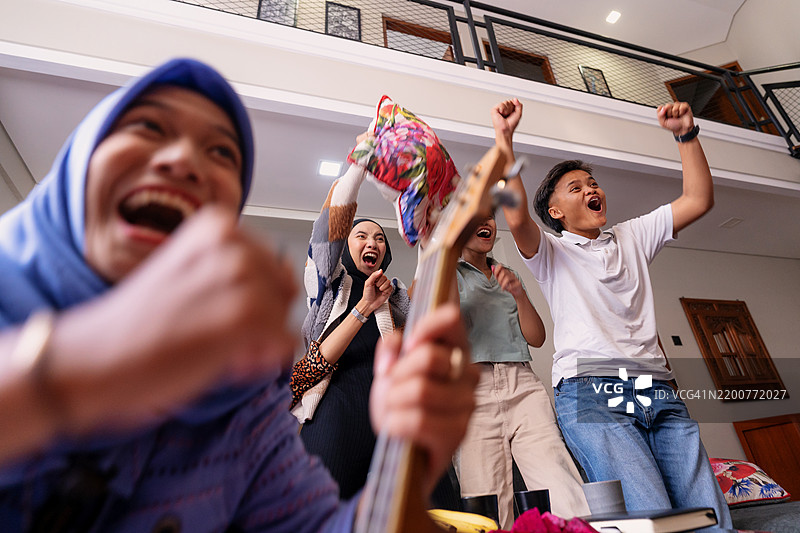 兴奋的多元化女性朋友们在看电视时欢呼图片素材
