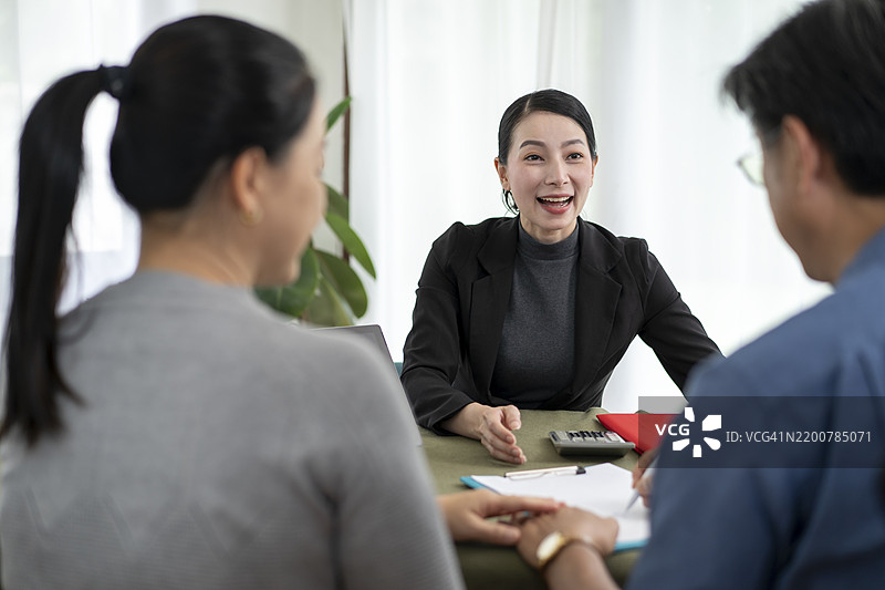 亚洲老年夫妇在家中接受专业理财顾问关于家庭财务规划、房地产保险或健康保险的建议后感到快乐和愉悦。图片素材