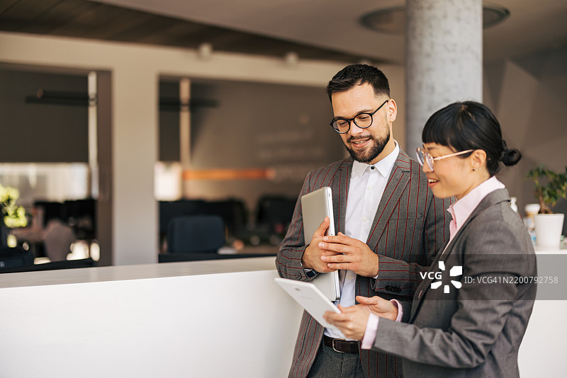 同事们在现代办公室讨论使用数字平板电脑的工作图片素材