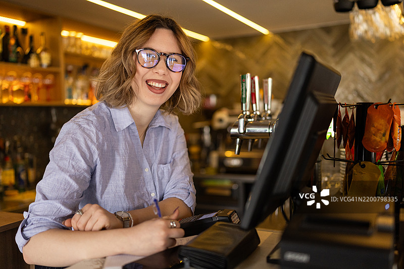 年轻女收银员在工作场所的肖像图片素材